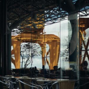 Reflective glass showing modern architecture in Nazaré, Brazil with vibrant yellow structures.