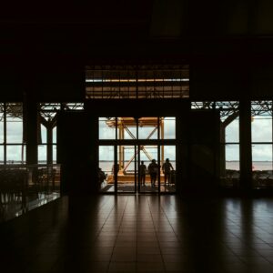 Silhouetted figures in a dark hallway leading to a bright outdoor view in Nazaré, Brazil.